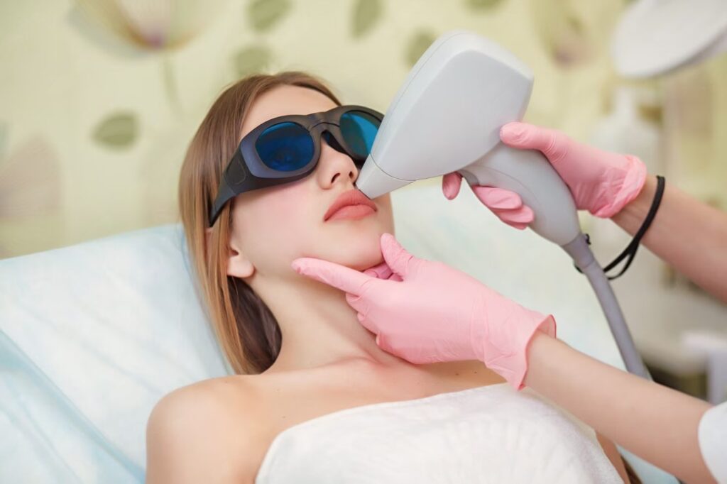 Woman undergoing PicoLazer treatment for skin rejuvenation, wearing protective goggles, with a technician applying laser technology in a clinical setting.