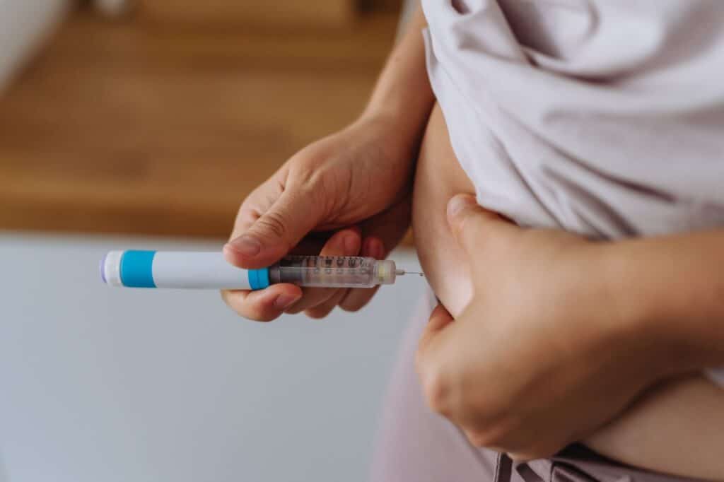 Person administering semaglutide injection into abdomen for weight management.